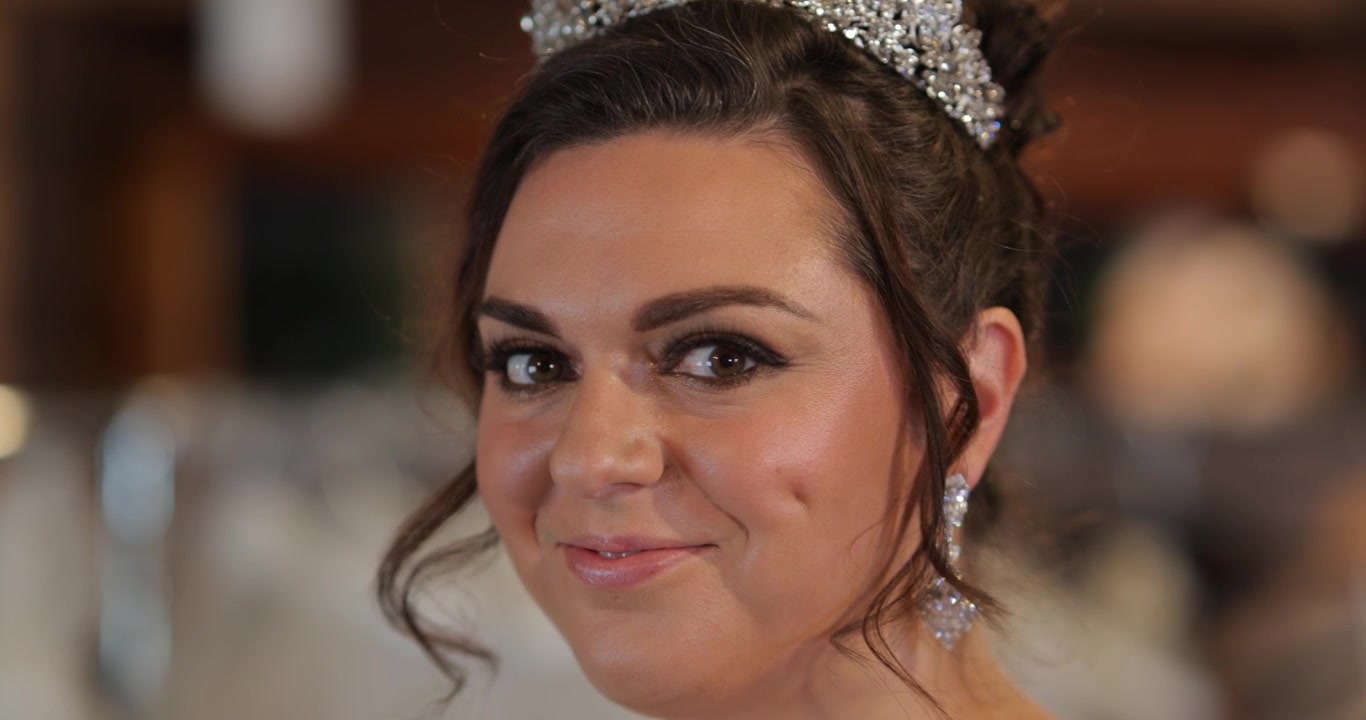 Primo piano di una modella sposa con le fossette, mentre riceve gli ultimi ritocchi ai capelli - sorridente - 4K.