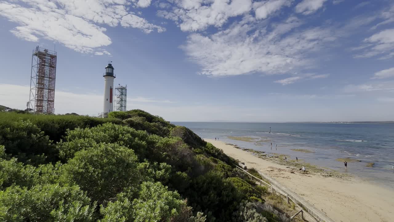 Queenscliff Lighthouse Overlooking A Beautiful Beach With People In Victoria, Australia.