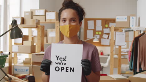 woman running a small business holding open sign