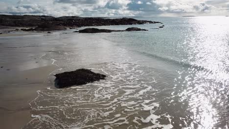 aerial view: waves crashing on the shore on a sandy beach in ireland, connemara