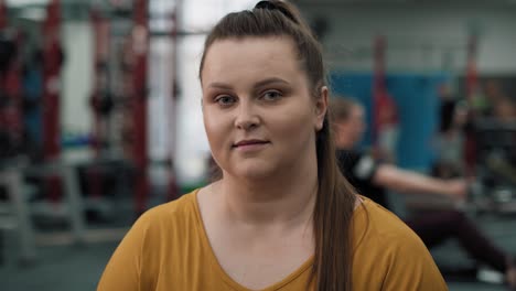 retrato de una mujer caucásica sonriente con sobrepeso en el gimnasio.
