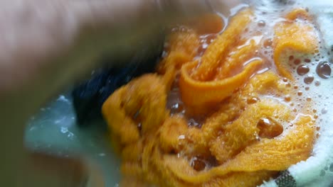 close-up of hand washing fabric in soapy water