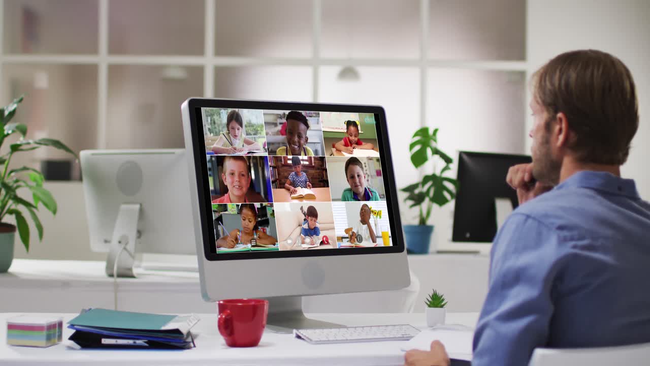 Caucasian male teacher using computer on video call with school children