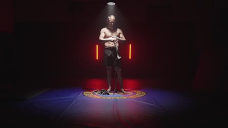 el tipo se pone vendajes para pelear, boxear, envolver la mano en el dojo, entrenamiento de artes marciales.