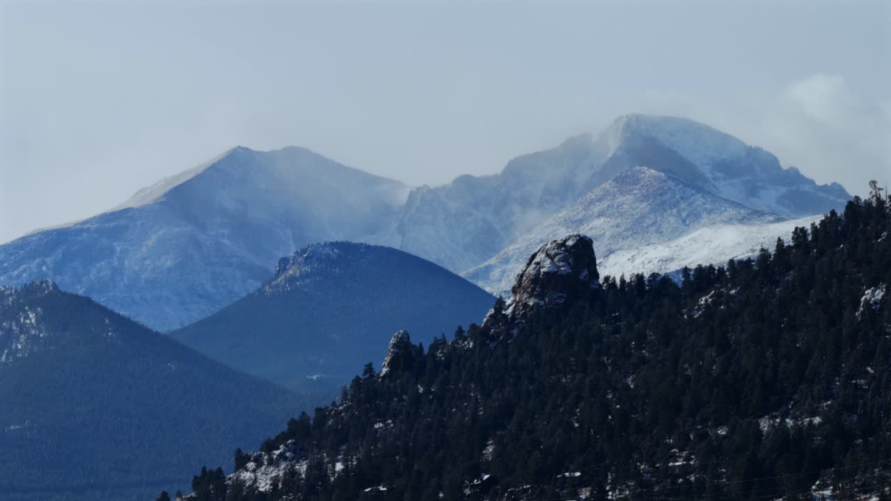 Fredda mattina d'inverno a Longs Peak, Estes Park, Kruger Rock, riprese aeree con drone. Neve fresca spazzata dal vento nel Parco Nazionale delle Montagne Rocciose del Colorado, cielo blu e nuvole. Front Range di Denver, picco prominente, movimento circolare a destra.