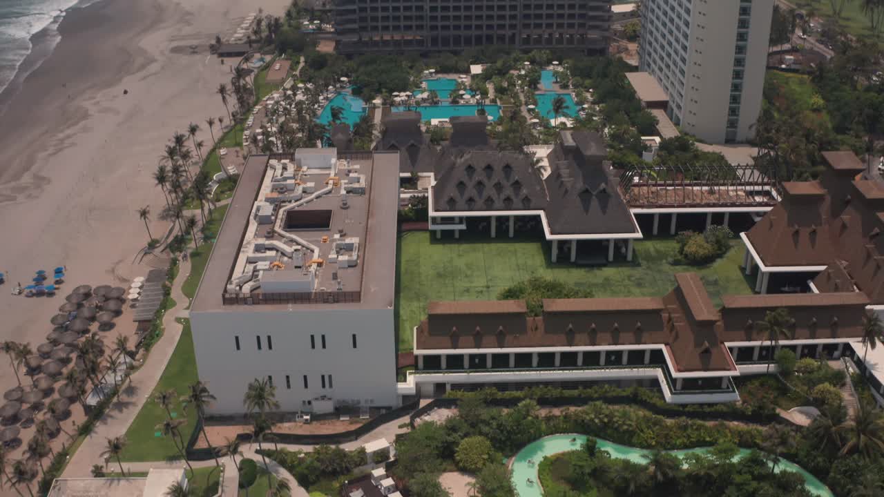 Vista aerea a volo d'uccello di piscine e fronte spiaggia di un lussuoso edificio residenziale ad Acapulco, Messico.