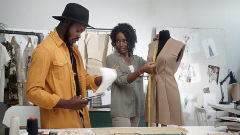 young man and woman clothing designers taking measurements of the dress with measuring tape