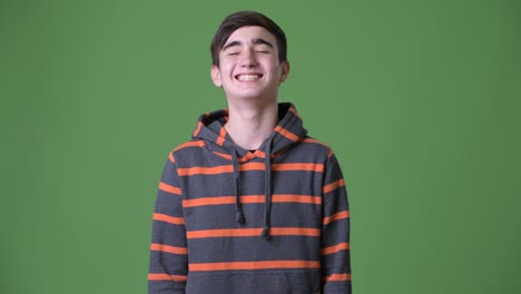 young handsome iranian teenage boy against green background