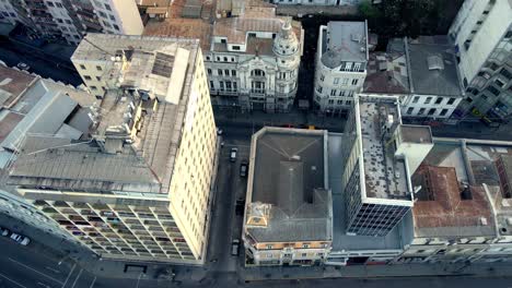 Aerial-tilt-up-lowering-on-Valparaiso-neighborhood-and-and-traffic-near-El-Mercurio-eclectic-building,-Chile