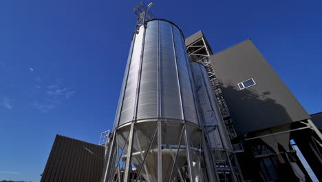 modern silos on blue sky background. large silver grain elevator outdoors. industrial territory of warehouse. agricultural storage and processing plant.