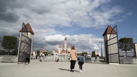 mother and daughter walking through park entrance