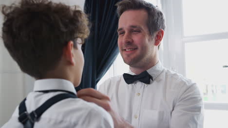 father and son wearing matching outfits getting ready for wedding at home