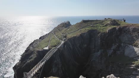 dramatic landscape with arched bridge across precipices, shimmering ocean and mizen head lighthouse, the view from visitors platform. west cork ireland