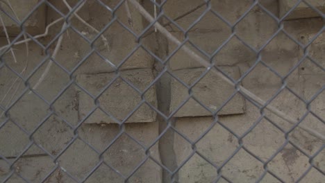 Camera-slowly-pulling-out-from-the-outside-stone-wall-through-the-chain-link-fence