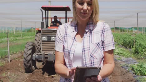 Video-Einer-Glücklichen-Kaukasischen-Frau,-Die-Mit-Einem-Tablet-Vor-Einem-Traktor-Steht