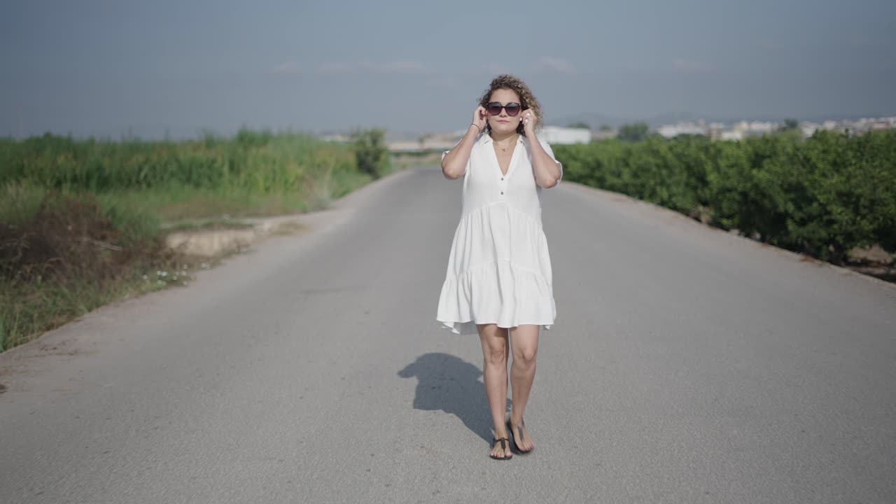 Woman walking on a country road in a white dress