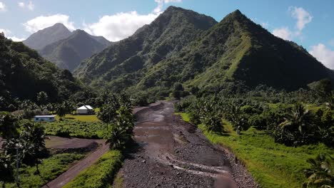 a washed out and eroded river bed leads into a spectacular valley with volcanic mountain peaks in tahiti