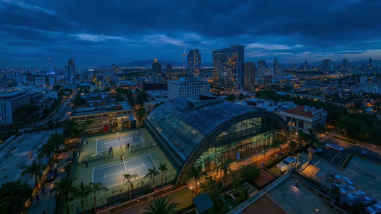 Pulling back as twilight deepening, camera panning to reveal downtown, glass dome and lit courts
