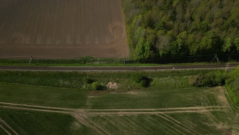 drone footage of a train passing through countryside with fields on either side of the tracks