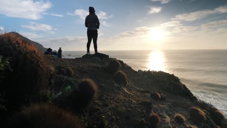 Viendo-La-Puesta-De-Sol-Desde-El-Borde-De-Un-Acantilado