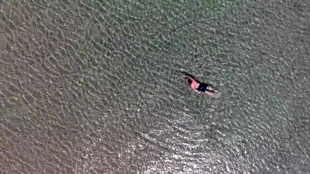 Aerial View of a Man Swimming in Clear Shallow Ocean Water