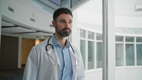 Bearded doctor walking clinic hallway closeup. Focused professional thinking