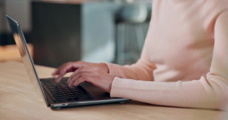 Donna che scrive al computer portatile su una scrivania in un interno moderno