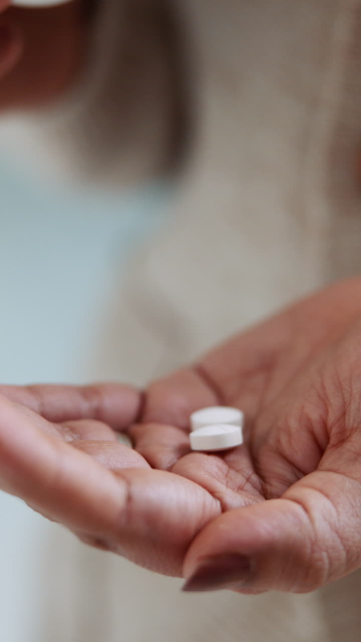 Persona vertiendo pastillas blancas de una botella en la mano