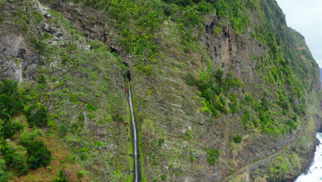 catarata en un acantilado en madeira con un escalador oceánico disparado por un avión no tripulado panorámicas olas mar nublado