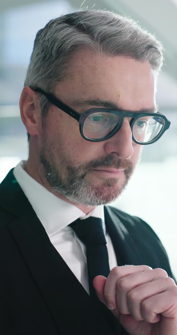 Professioneller Geschäftsmann richtet im Büro seine Brille und seinen Anzug