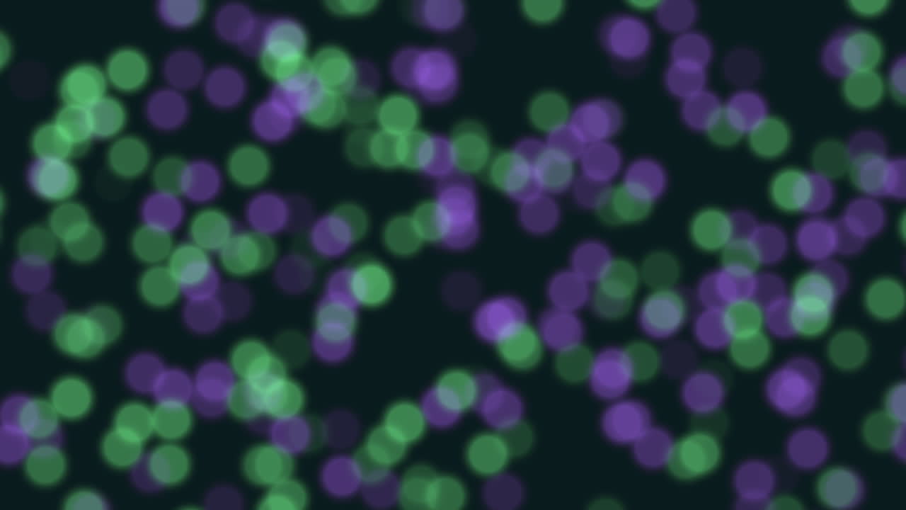 Defocused green and purple bokeh lights move softly on a dark background, creating a dreamy abstract backdrop ideal for celebrations, parties, presentations, titles and modern motion design projects