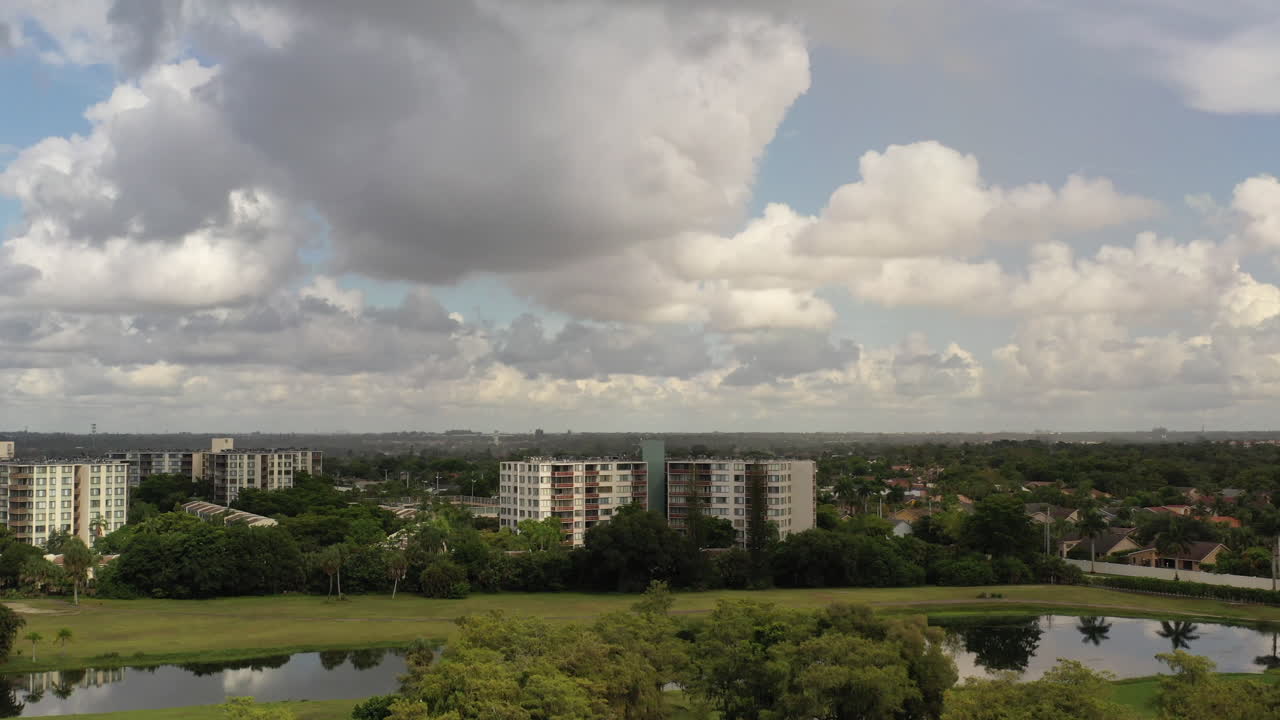 una vista aérea de un estanque reflectante, rodeado de edificios de apartamentos blancos y hierba verde en un día soleado en florida