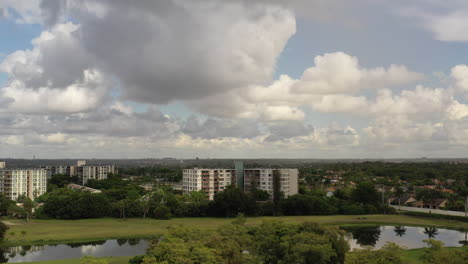 An-aerial-view-of-a-reflective-pond,-surrounded-by-white-apartment-buildings-and-green-grass-on-a-sunny-day-in-Florida