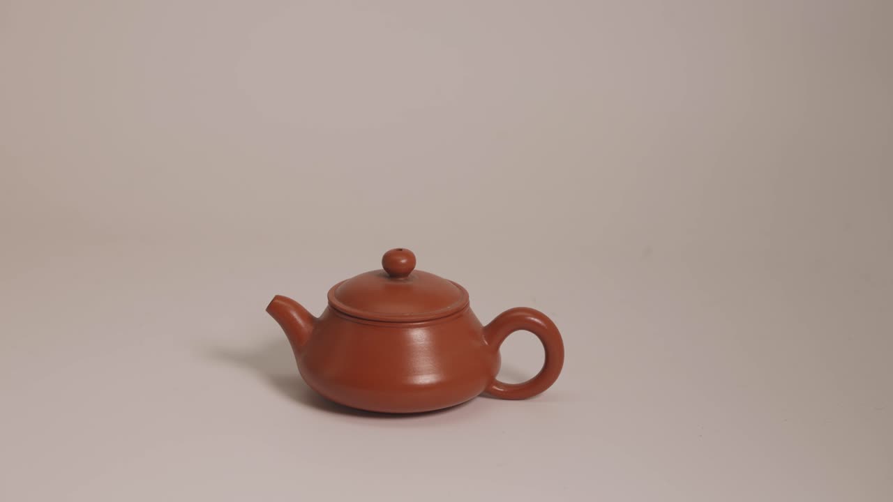 A red ceramic tea pot on a white pot.
