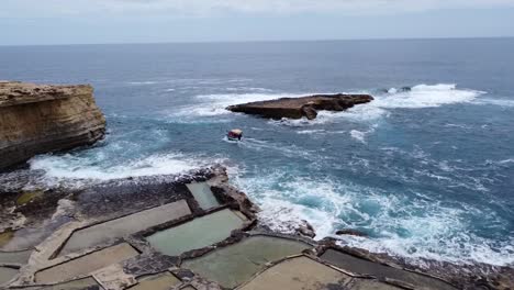 drone view of a small boat near salt pans and cliffs in malta