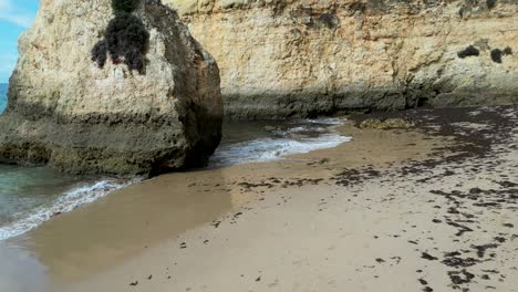 sandy beach in portugal with waves gently lapping against the rocky cliffs and shoreline