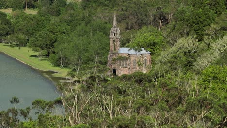 Capilla-Frente-Al-Lago-De-Nuestra-Señora-De-Las-Victorias-Con-Un-Exuberante-Paisaje-Natural-Verde-En-Furnas,-Sao-Miguel,-Azores,-Portugal