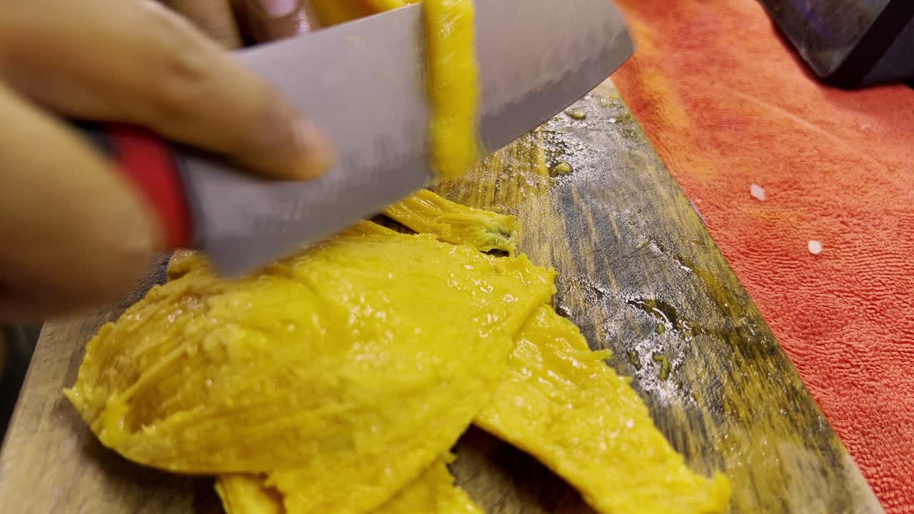 Fette di mango fresco su un tagliere di legno, consistenza matura e succosa.