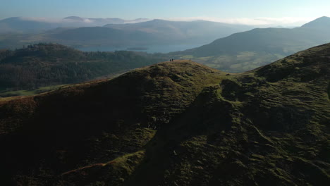 Hikers-on-distant-hillside-with-orbit-revealing-misty-mountains-with-natural-lens-flare-at-English-Lake-District