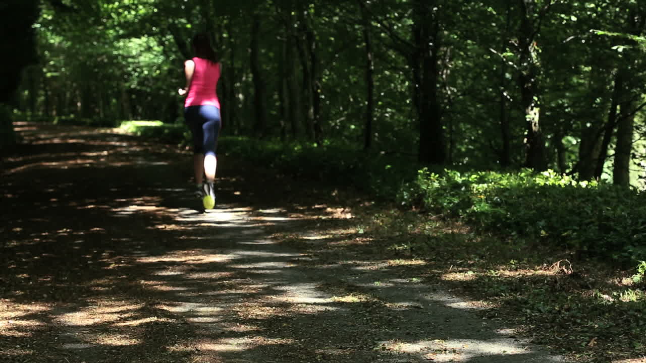 una morena en forma corriendo por un bosque.
