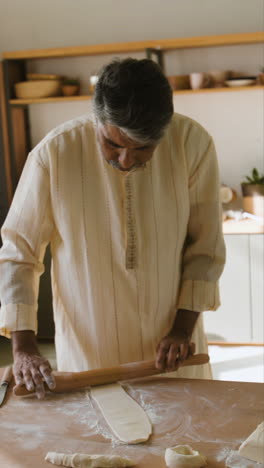 indian man rolling dough in kitchen