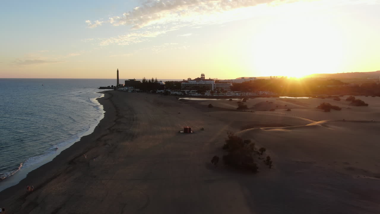 Scenic aerial footage of the Maspalomas lighthouse and sand dunes at sunset in Gran Canaria