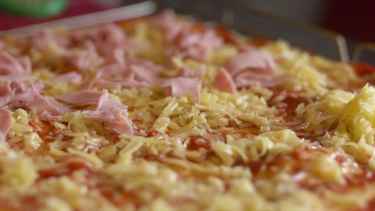 Aggiunta di prosciutto su una pizza prima di infornarla