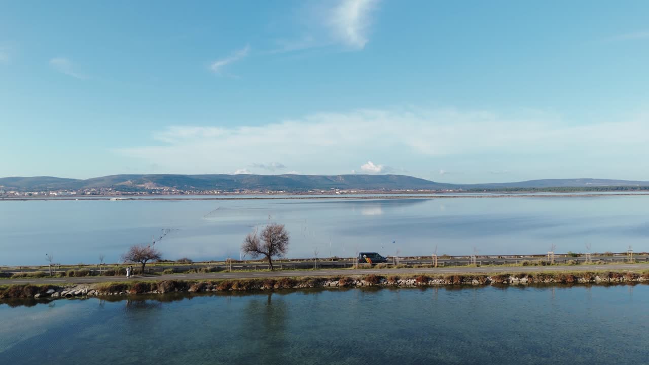 Aerial tracking shot of a van driving along a highway over a lake in France
