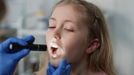 Girl patient opening mouth for throat examination closeup. Cute child visiting