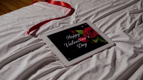 tablet with happy valentine's day message on a bed