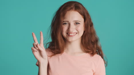 ragazza dai capelli rossi che guarda la telecamera sullo sfondo turchese.