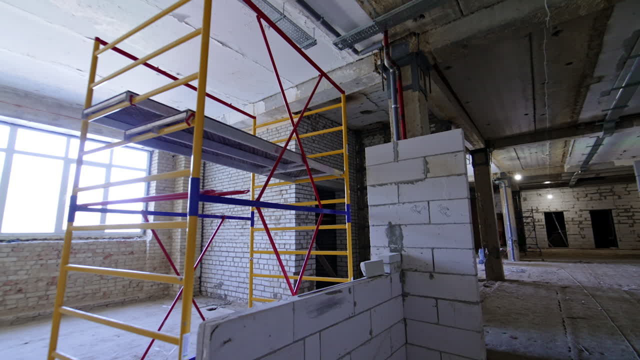 Scaffolding inside the premises of the constructed building. White brick walls newly built in the interior.