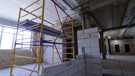 scaffolding inside the premises of the constructed building. white brick walls newly built in the interior.