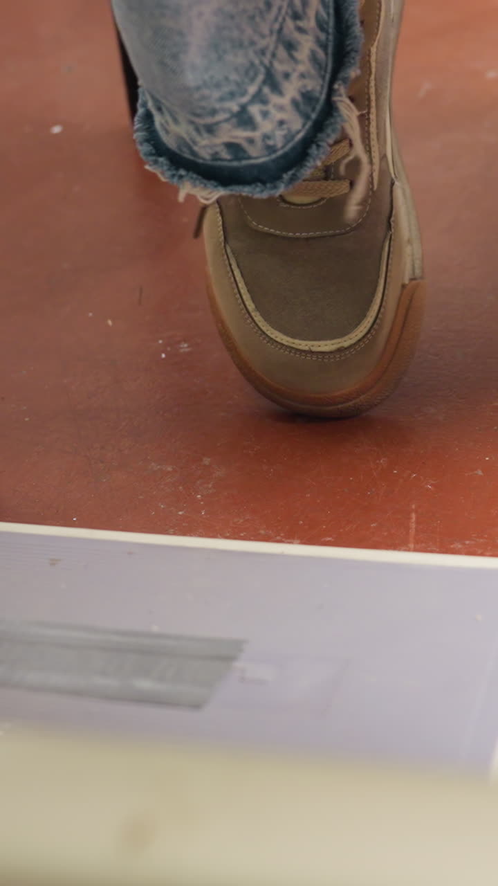 Denim steps on stage, Casual wear moves to lively rhythms, Worn denim sneaker dancing on vibrant studio flooring, Closeup of frayed jeans and energetic foot movement during rehearsal session